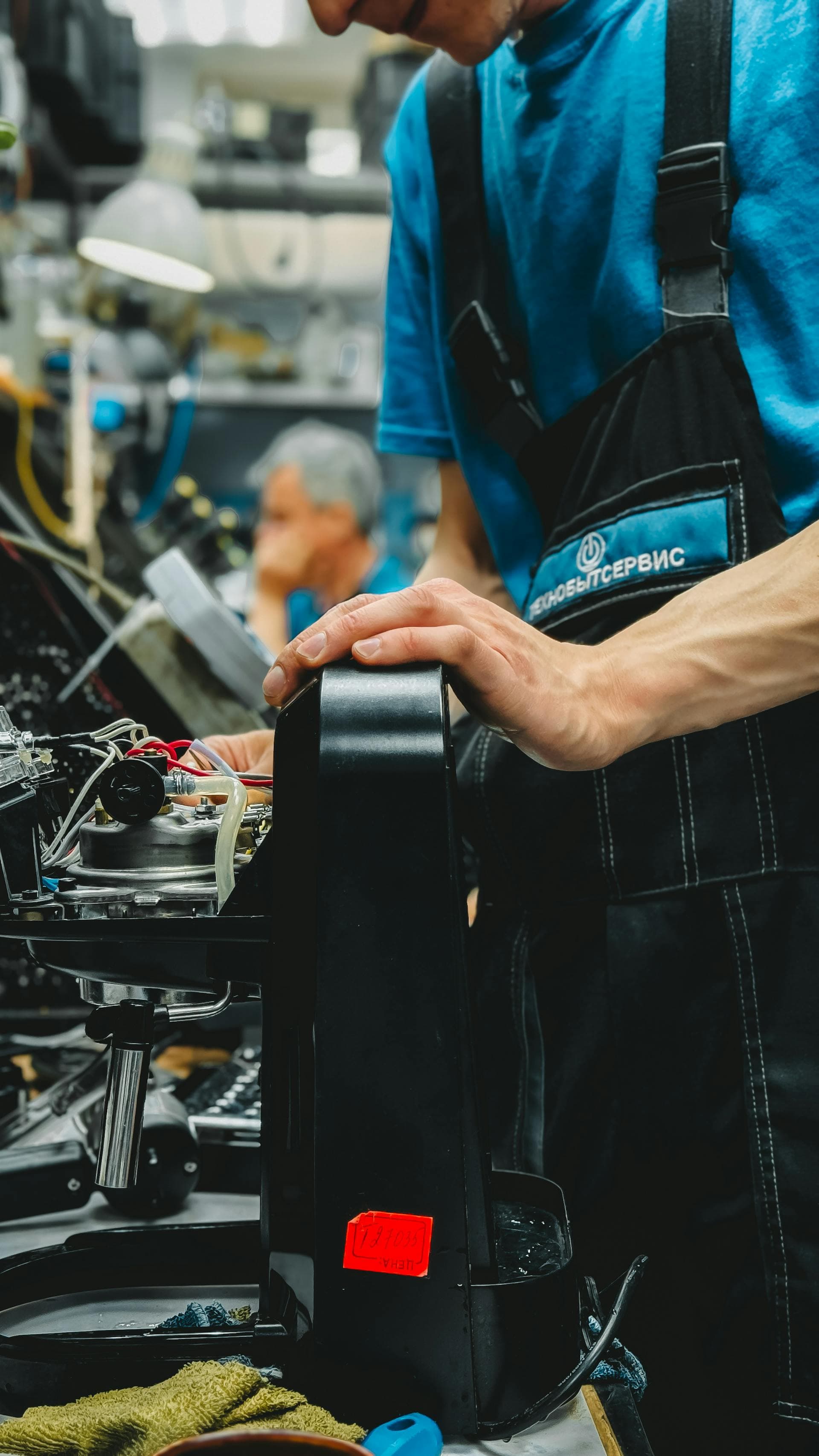 Technician repairing a commercial coffee machine on a workshop bench